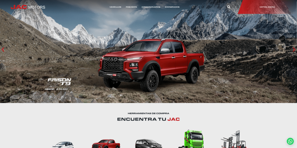Red JAC pickup truck in mountainous terrain with snow-capped peaks in the background.