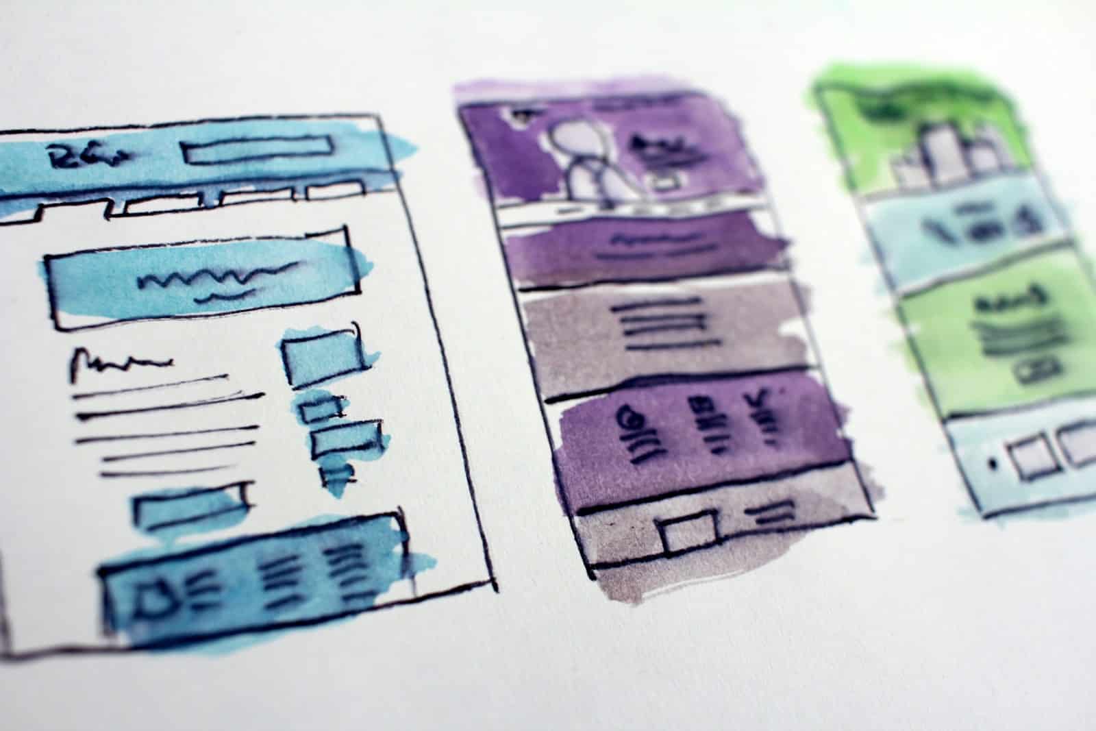 Watercolor sketches of three website layouts with blue, purple, and green themes on white paper.